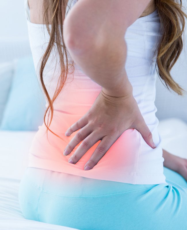 Image of a woman with back pain which is highlighted in red.